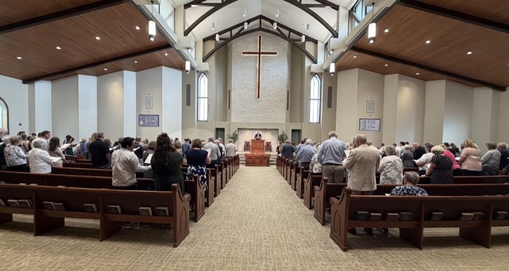 The congregation gathered for worship, facing the pulpit and cross at the front of the sanctuary